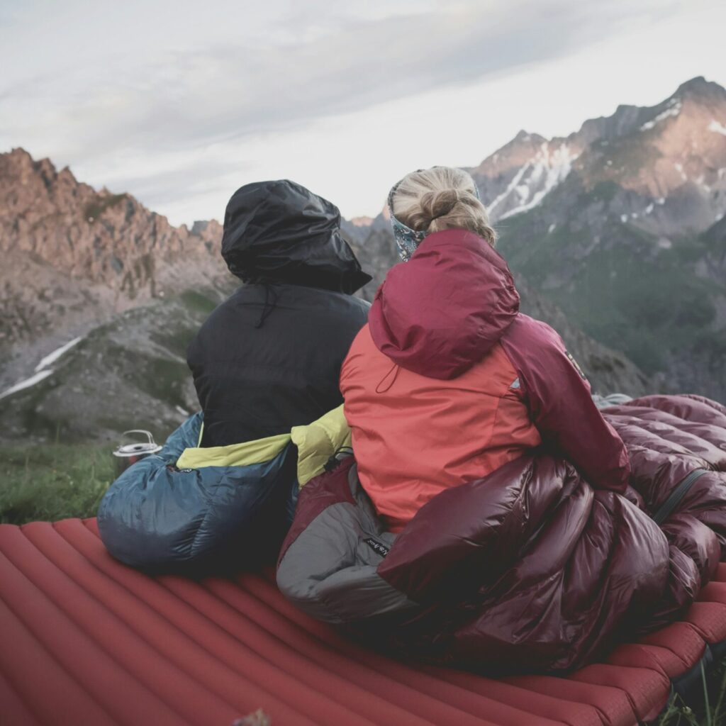 Two people sitting up in sleeping bags